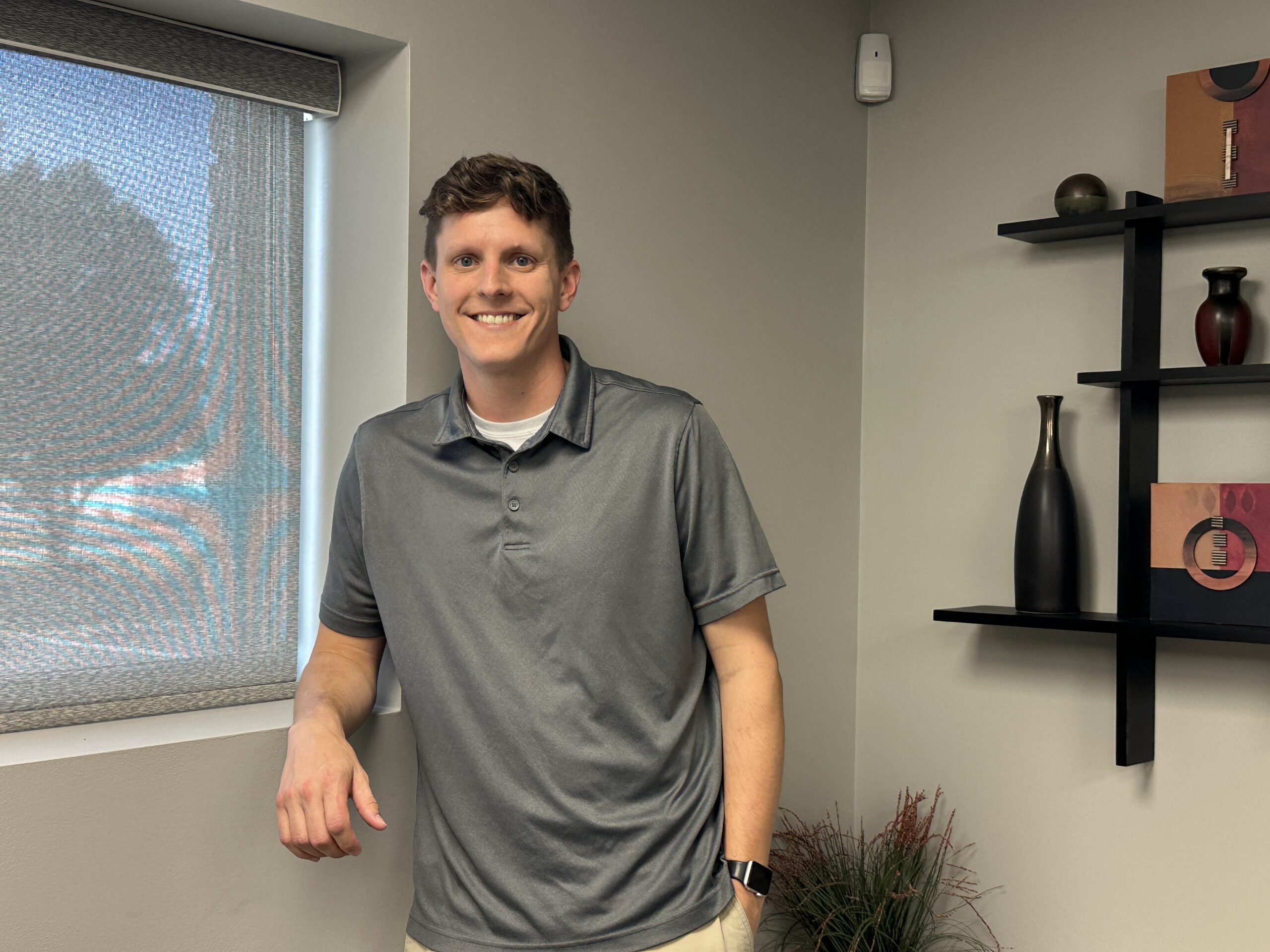 Friendly looking case manager is standing next to a nicely decorated wall smiling into the camera