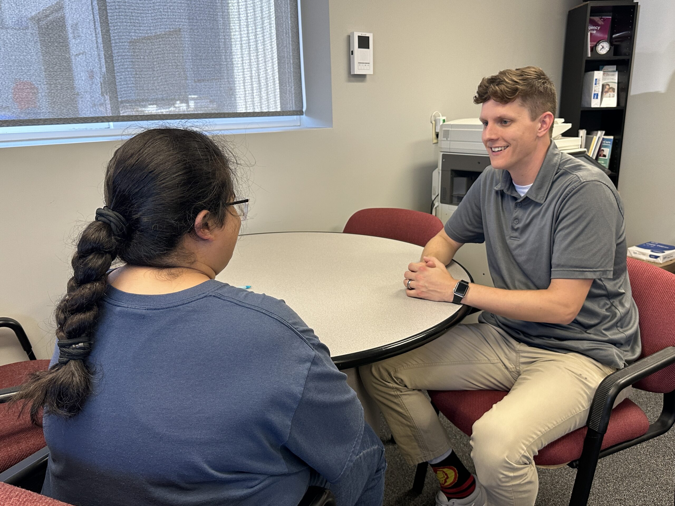 Case manager is sitting at a table with a client discussing services